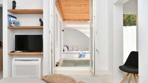 Een moderne slaapkamer met een televisie, een boekenkast, een bed en een zithoek met uitzicht op de omgeving.