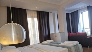 A hotel room with a large bed, a wardrobe, a sofa, and a hanging light fixture.