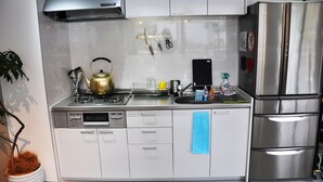 Uma cozinha moderna com eletrodomésticos de aço inoxidável, incluindo uma geladeira e lava-louças, e uma chaleira sobre a bancada.