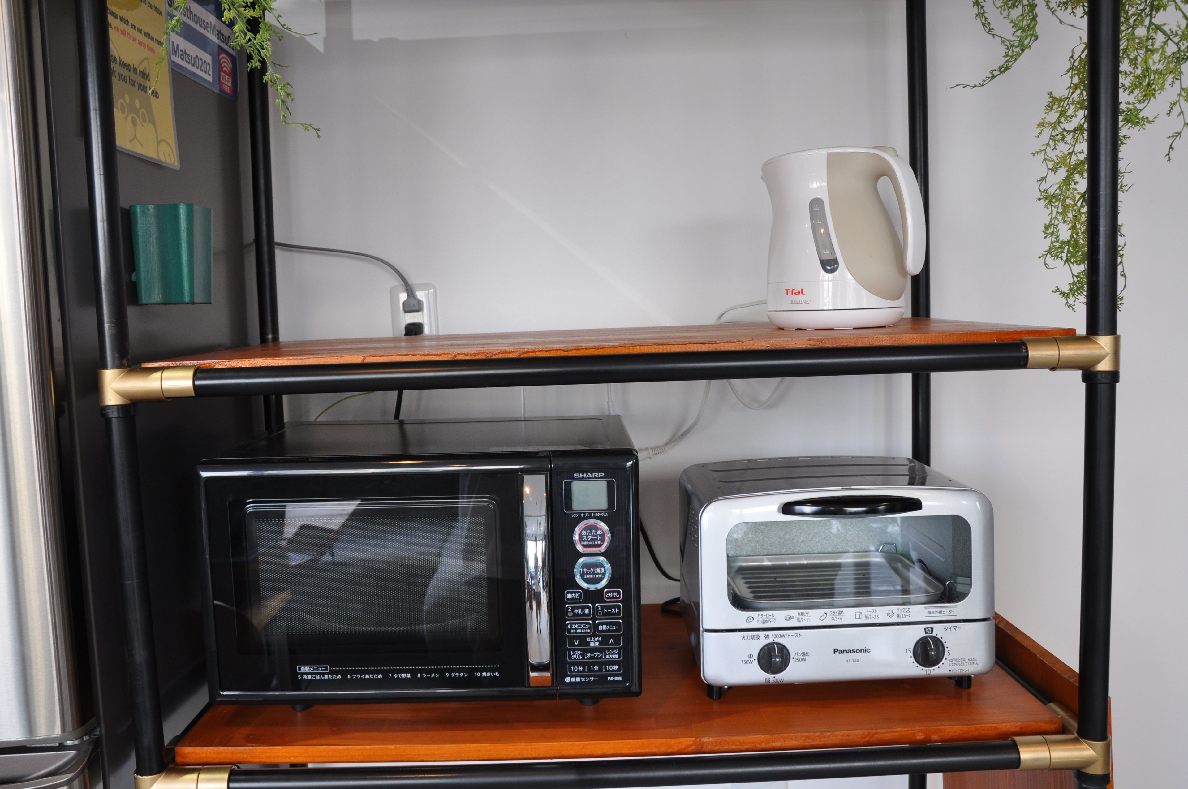 Une petite cuisine équipée d’un micro-ondes, d’un grille-pain et d’une bouilloire, le tout placé sur une étagère.