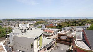 A high-rise hotel with multiple floors, a rooftop terrace, and a view of the surrounding cityscape and hills. - Hotel Bibi - Adults Only (Kashiba)