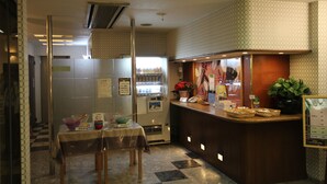A small, clean kitchen area with a refrigerator, a microwave, and a coffee machine. There is a table with a few items on it, and a counter with a plant and a menu. - Hotel Bibi - Adults Only (Kashiba)