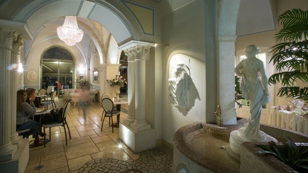 An interior with a fountain, statues, and a dining area with tables and chairs. - Palazzo Bove (Galatone)