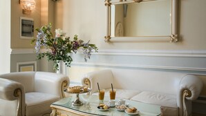 A dining area with a glass table, white upholstered chairs, a vase of flowers, and a mirror on the wall. - Palazzo Bove (Galatone)