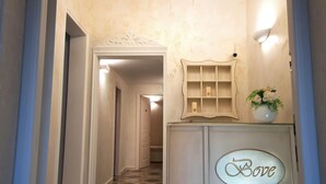 A hallway with a chandelier, a cabinet with the word "Love" on it, and a patterned floor. - Palazzo Bove (Galatone)