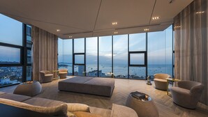 Un salon moderne doté d’une grande baie vitrée panoramique, d’un ensemble de canapés et d’une table basse.