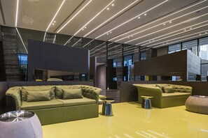 A modern interior with a green sofa, a yellow table, and a metallic lamp.