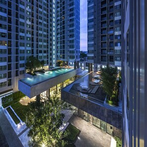 A modern high-rise building with a rooftop swimming pool and outdoor seating area.