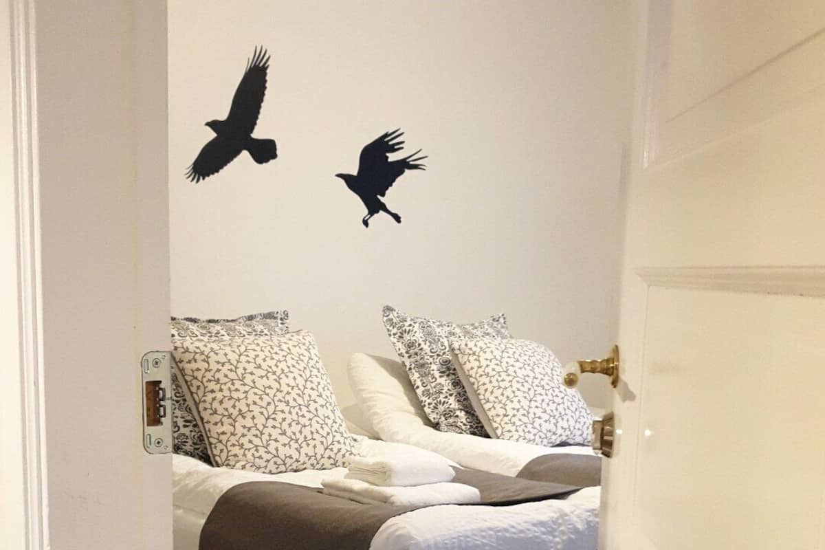 Ein Schlafzimmer mit einem Bett, Kissen und einer Wanddekoration mit zwei Vögeln.
