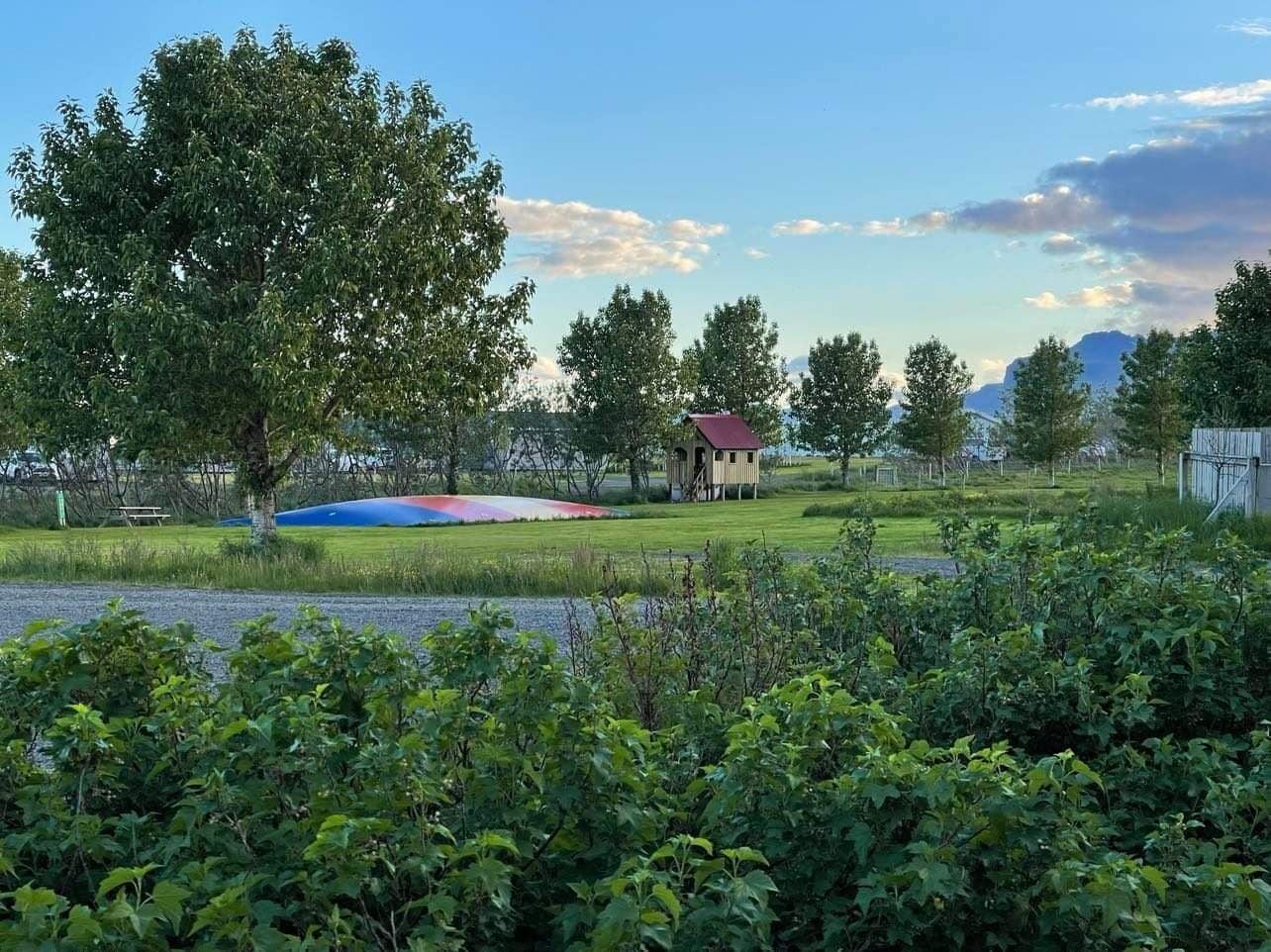 A park with a small pavilion, a colorful mural, and a lake.