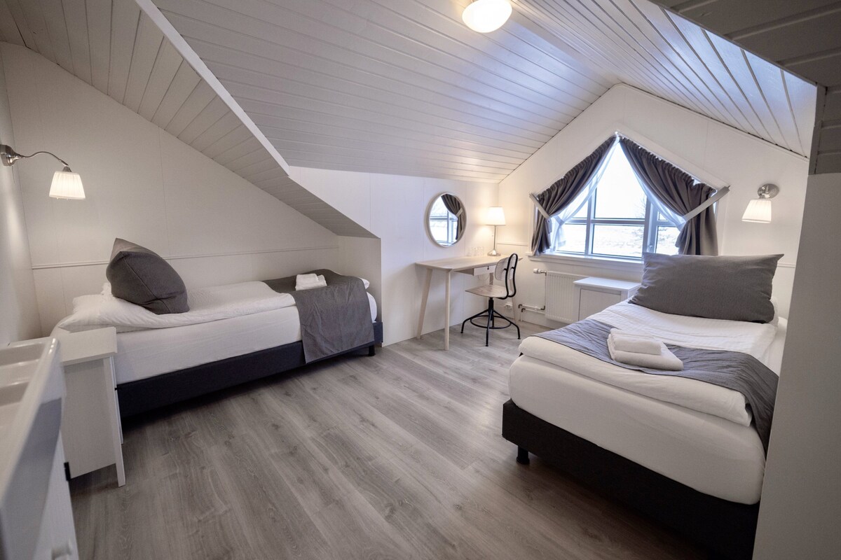 A room with two beds, a desk, and a chair.