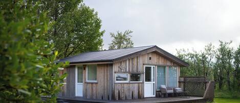 A wooden cabin with a deck and outdoor seating.