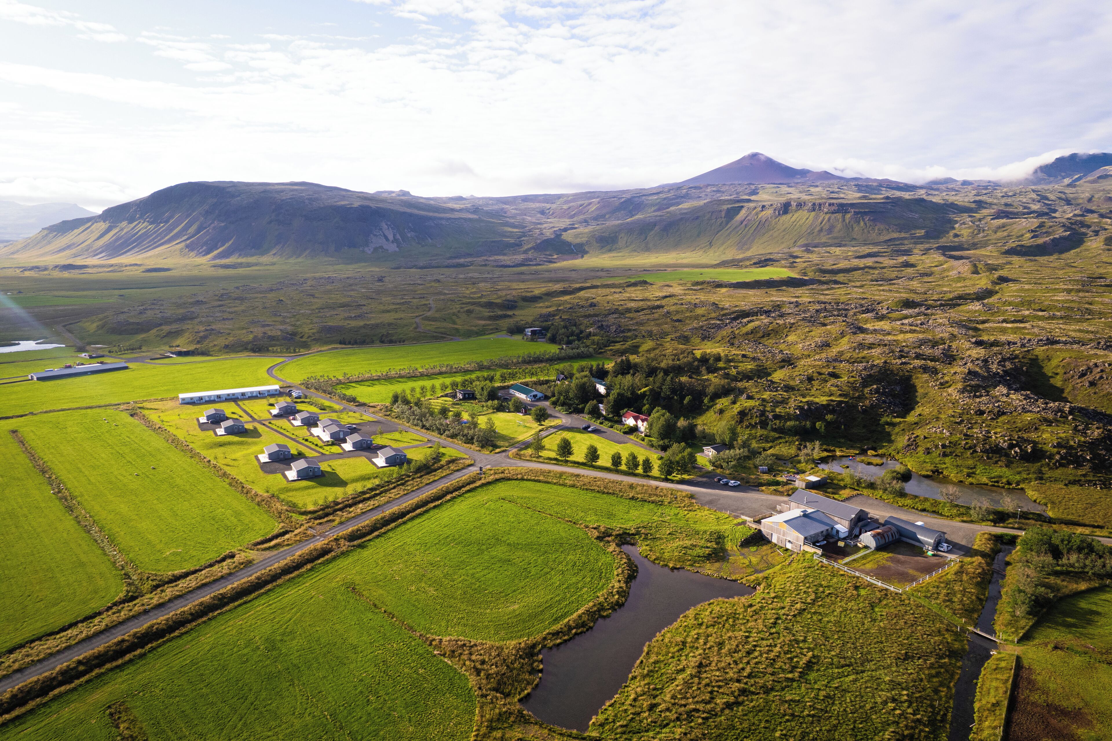 An aerial view of a rural landscape with fields, a small village, and a mountain in the background.