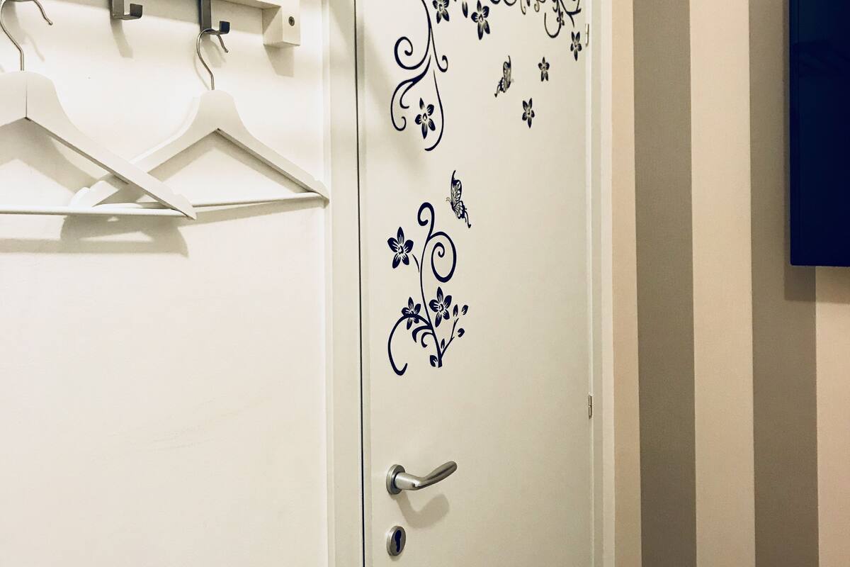 A white door with floral decals, a metal handle, and a hanging rack above it.