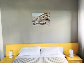 A hotel room with a bed, two bedside tables, a wall-mounted picture, and a window.