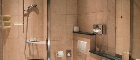A modern bathroom with a glass-enclosed shower, a white sink, and a toilet.