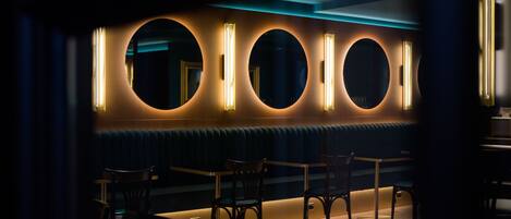 A dimly lit bar area with circular mirrors and seating.