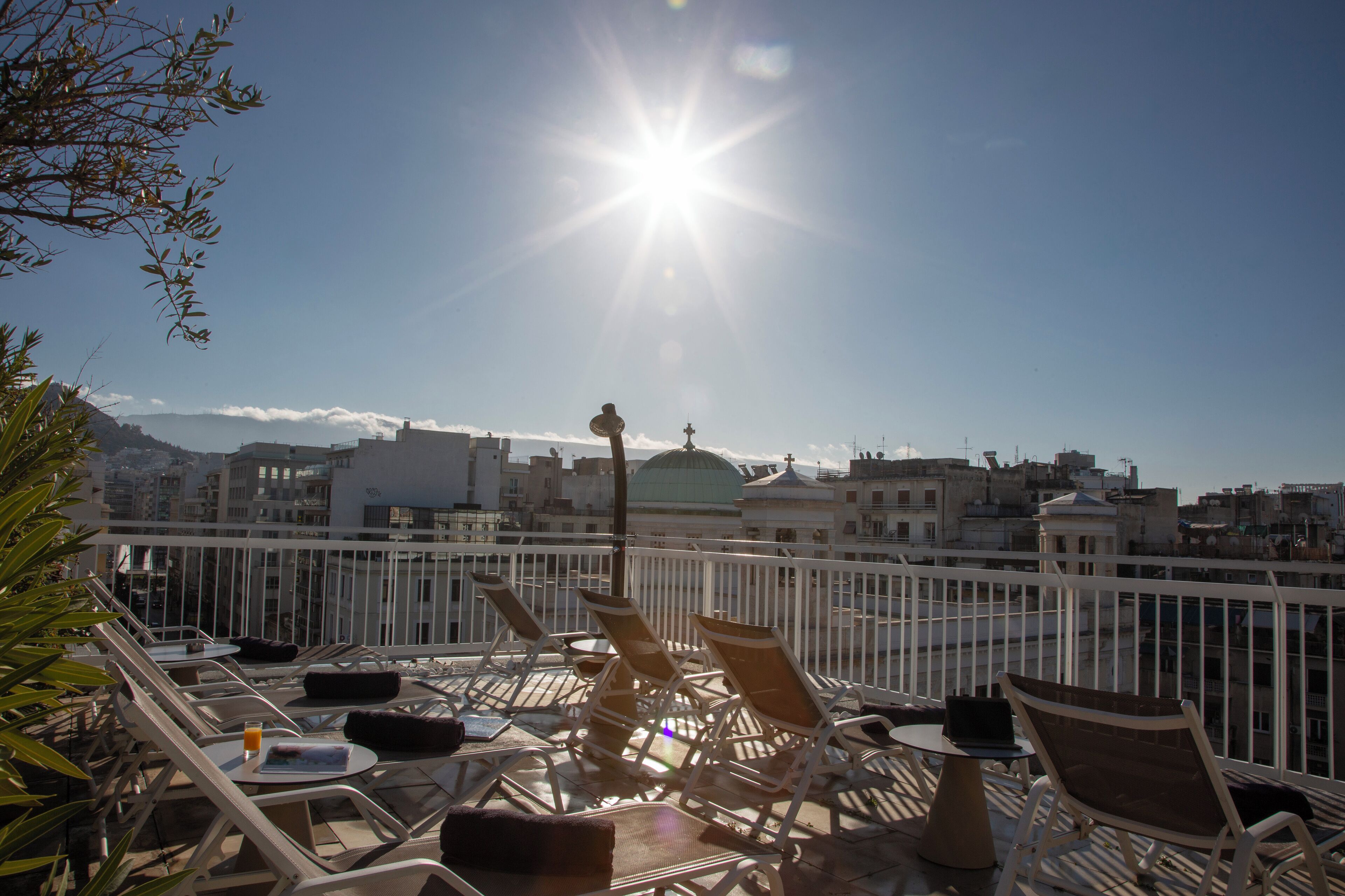 Terraço no telhado com espreguiçadeiras, uma mesa e vista para a cidade.