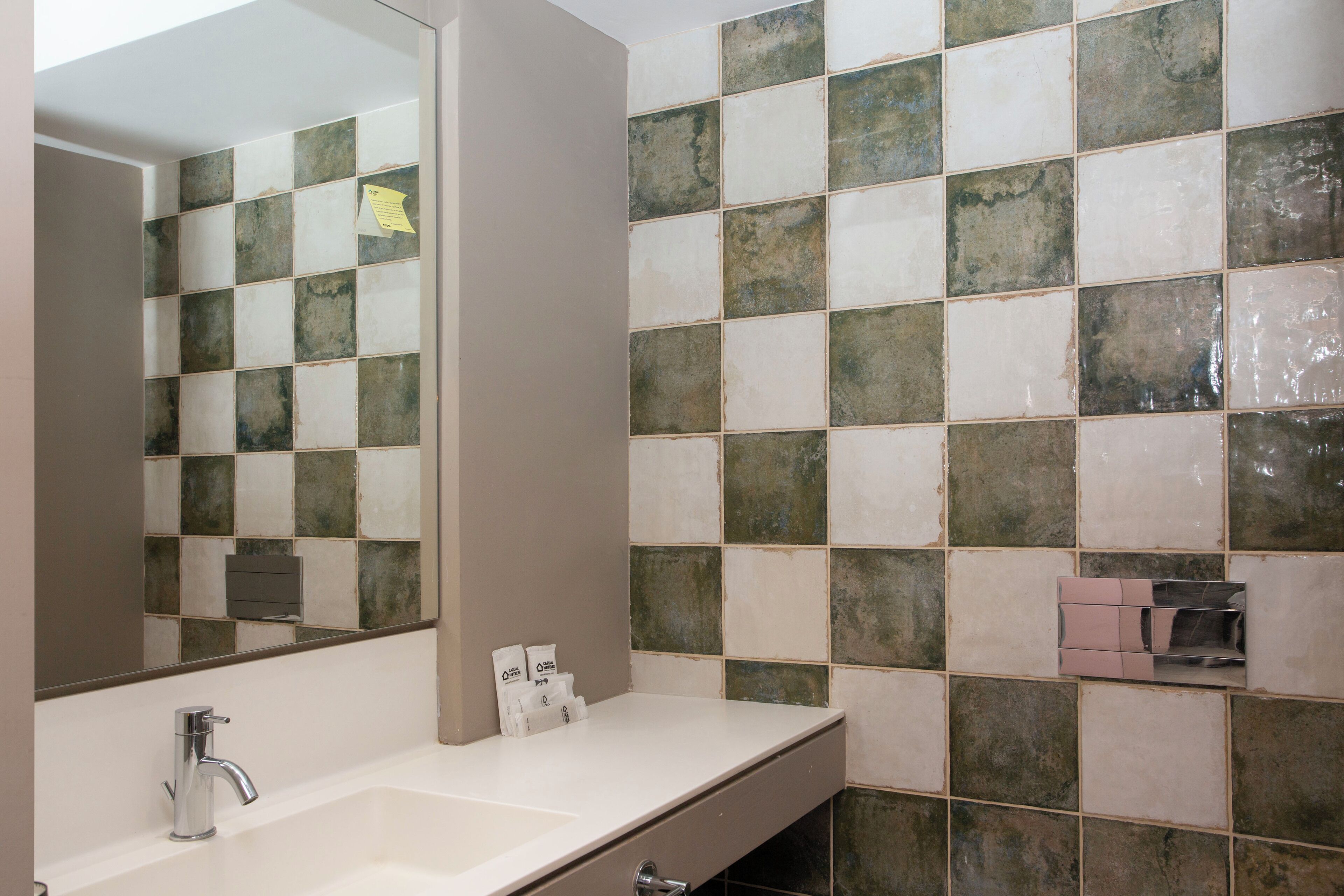 A bathroom with a white sink, a mirror, and a tiled wall.