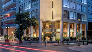 Un hôtel à plusieurs étages, doté d’un design moderne, avec des balcons aux étages supérieurs et une entrée imposante abritée.