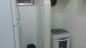A small kitchen with a gas stove, a refrigerator, and a trash bin. - Studio Maximo (Rio de Janeiro)