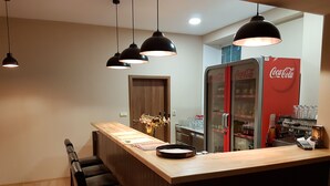 A bar area with a wooden counter, black bar stools, and a Coca-Cola refrigerator. - Villa Grohmann (Lipova-Lazne)