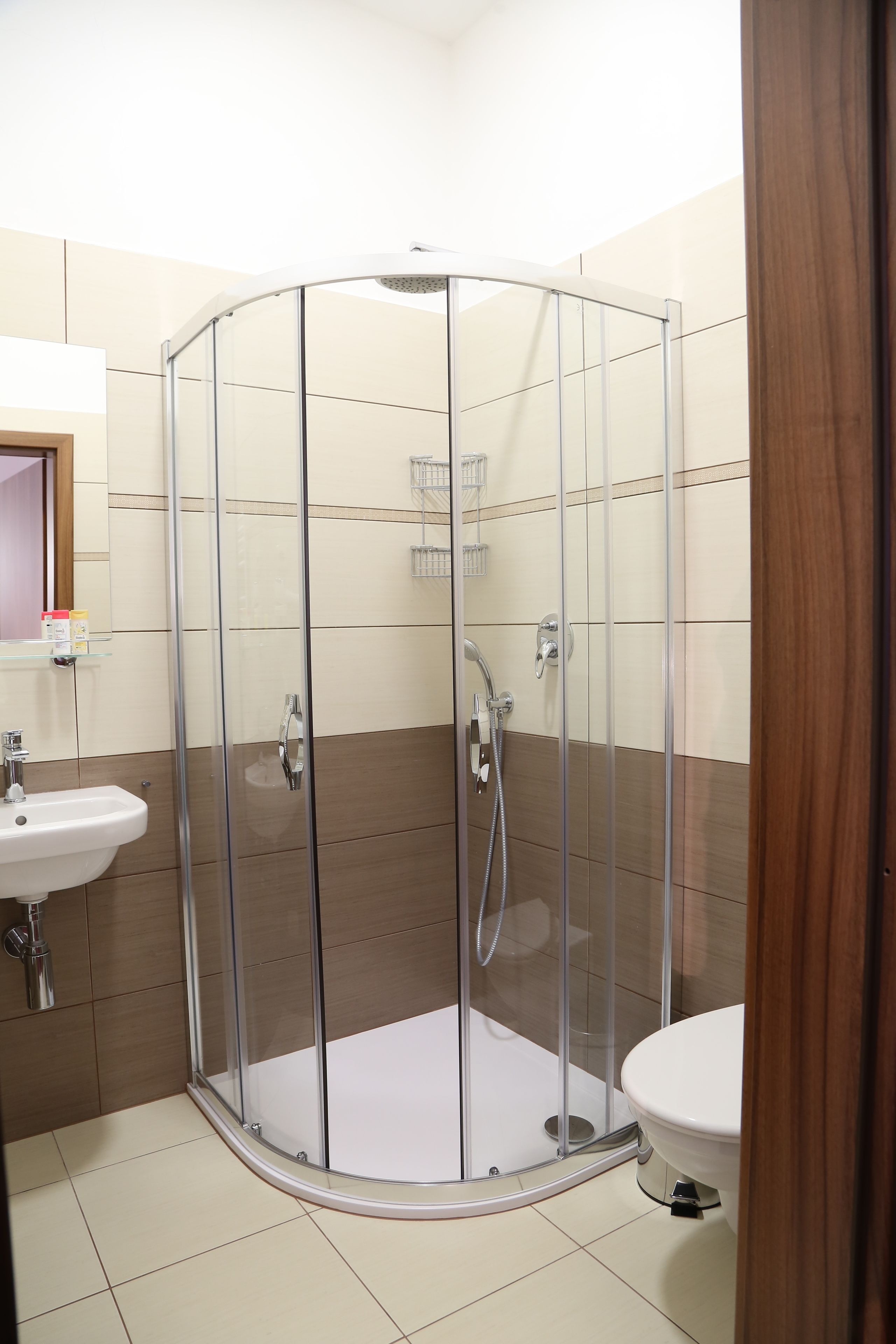 A bathroom with a glass-enclosed shower, a sink, and a toilet.