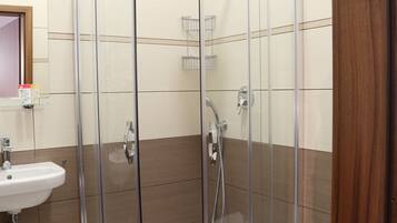 A bathroom with a glass-enclosed shower, a sink, and a toilet.