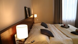 A hotel room with a neatly made bed, a bedside lamp, and a window with curtains. - Villa Grohmann (Lipova-Lazne)