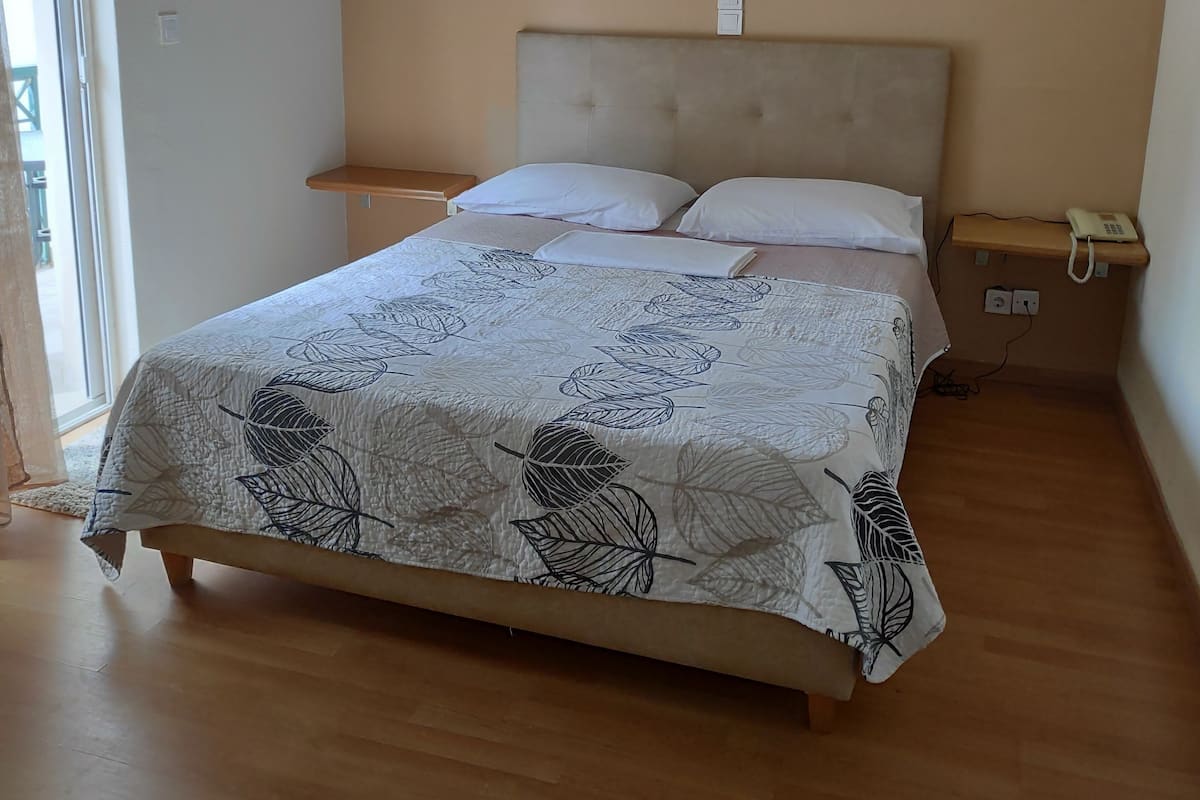 A bedroom with a bed, bedside tables, and a window.