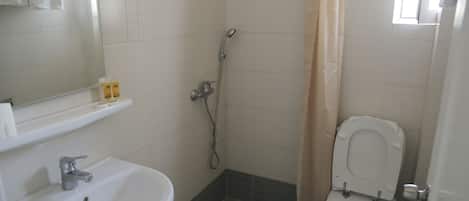 Un baño con lavamanos, inodoro, ducha y espejo.