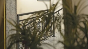 A staircase with a metal railing, a framed picture on the wall, and a plant in the foreground. - Hotel Anesi (Metamorfosi)