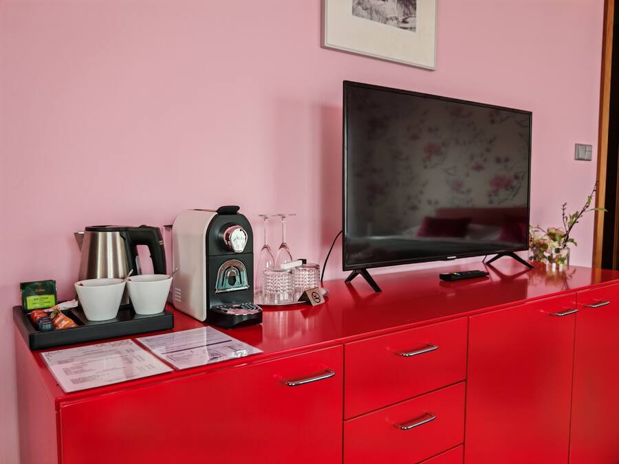 Ein roter Schrank mit einer Kaffeemaschine, zwei Tassen, einer Glas-Kaffeekanne und einer Fernbedienung.