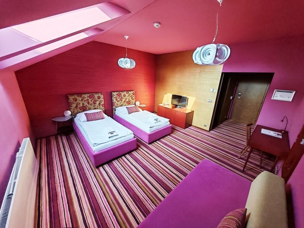 Ein Hotelzimmer mit zwei Betten, einem Fernseher, einem Schreibtisch und einem Sessel.