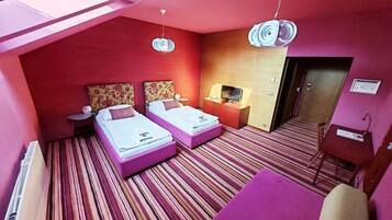 Ein Hotelzimmer mit zwei Betten, einem Fernseher, einem Schreibtisch und einem Sessel.