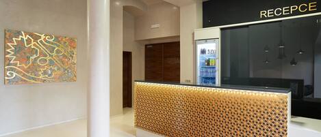 Un área de recepción con diseño moderno, que incluye un mostrador de patrón geométrico y una obra de arte montada en la pared.