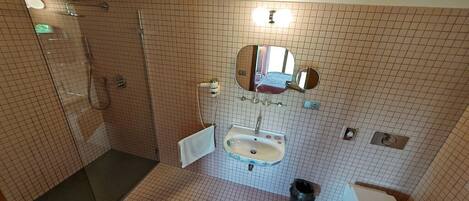 Un baño con ducha, lavabo e inodoro.