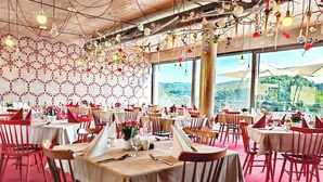 Un restaurante con varias mesas dispuestas para comer, que cuenta con una alfombra roja y vistas al exterior con vegetación.