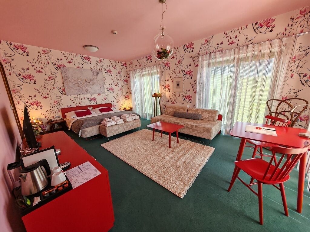 Un dormitorio acogedor con cama, sofá, mesa de comedor y una silla roja.