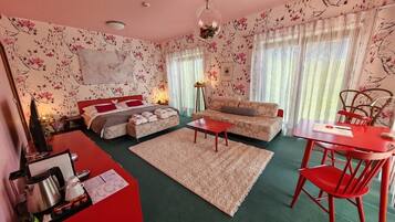 Un dormitorio acogedor con cama, sofá, mesa de comedor y una silla roja.