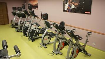 En rad med motionscyklar i ett gym, med en affisch på väggen.