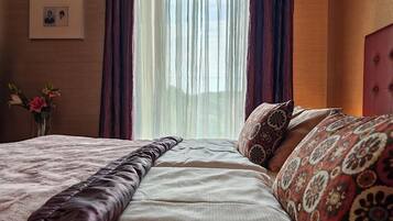 Una cama bien hecha con almohadas estampadas, un jarrón con flores y una foto enmarcada en la pared.