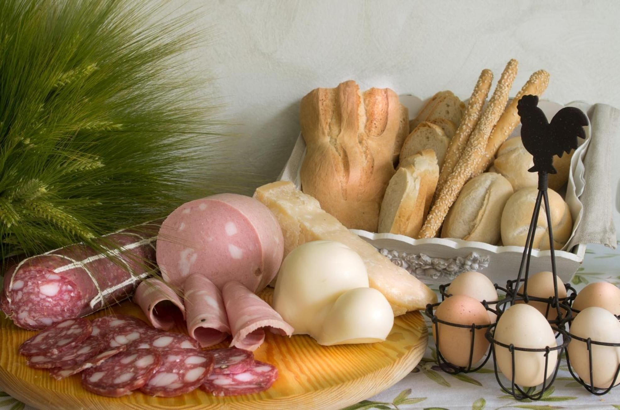 A variety of food items including salami, cheese, bread, and eggs on a wooden board.