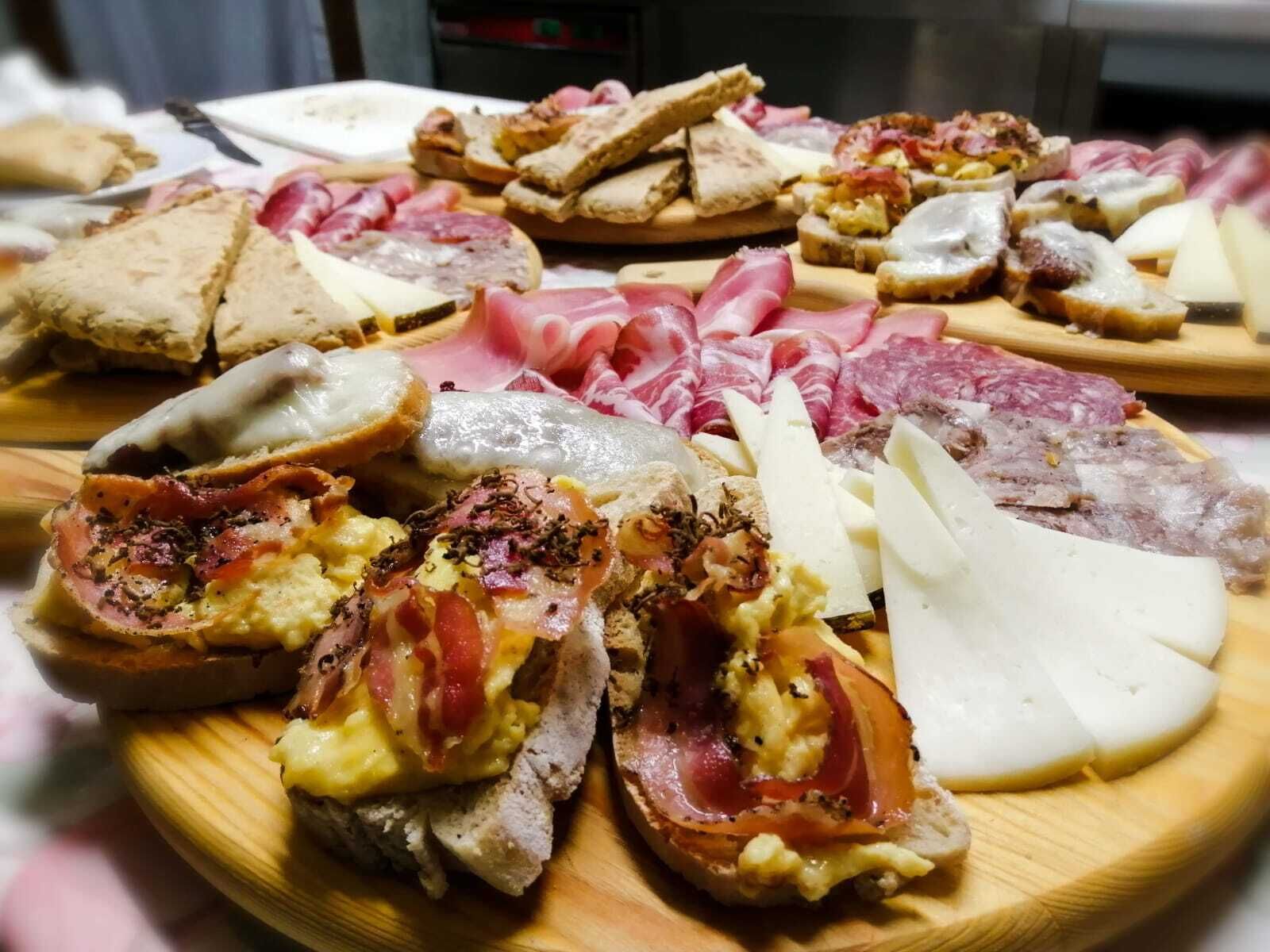 Diversos alimentos como pan, queso y embutidos sobre tablas de madera.