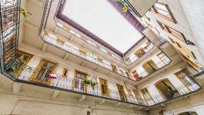 A multi-story building with balconies, arched doorways, and a central skylight. - happy home Budapest JOY (Budapest)