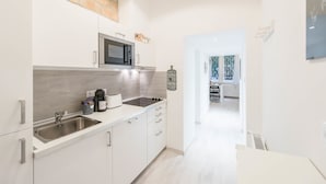 A modern kitchen with white cabinetry, a stainless steel sink, and a microwave. There is a sign on the wall that reads "Home." - happy home Budapest JOY (Budapest)
