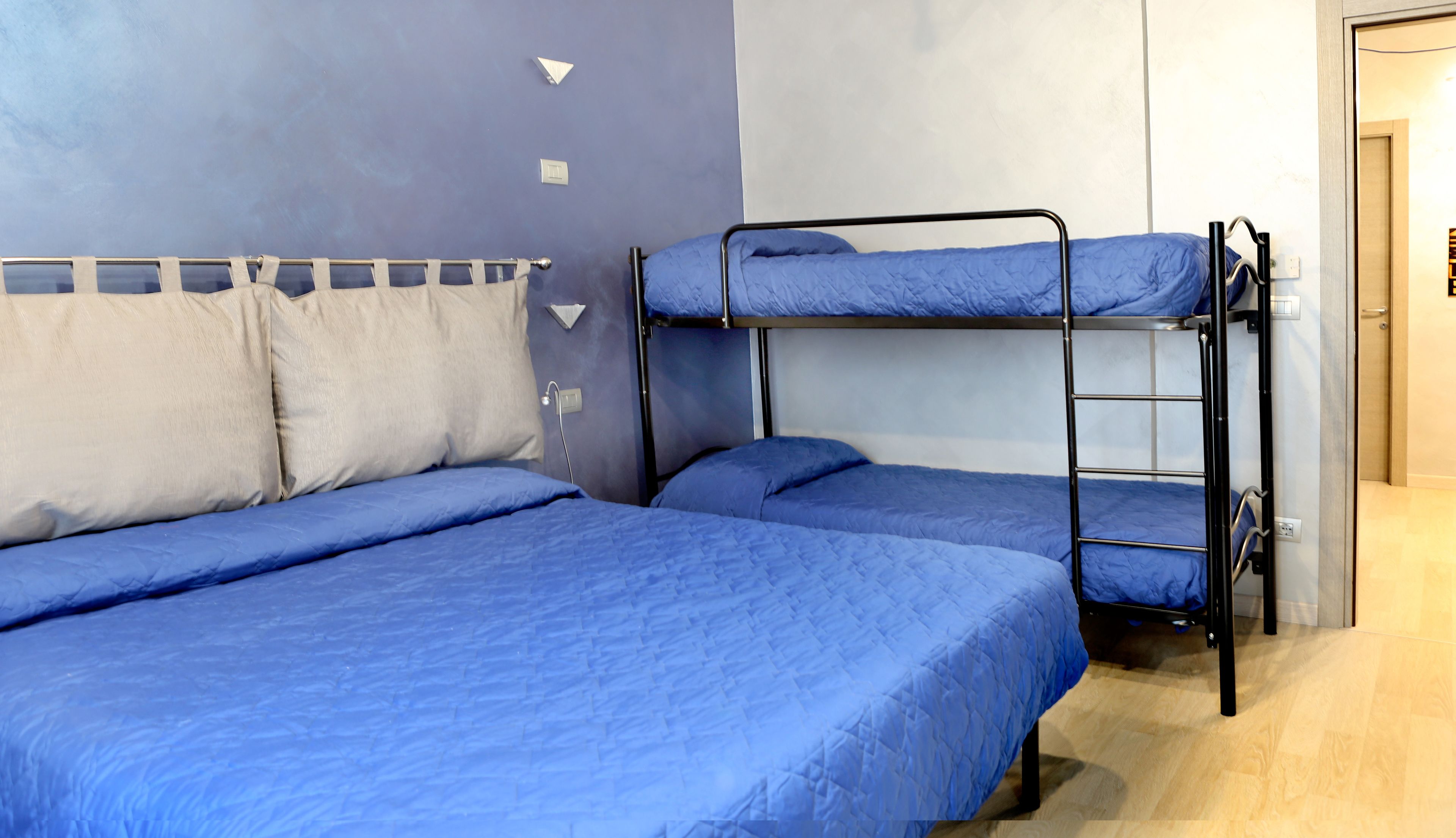 Una habitación con dos literas, cada una con ropa de cama azul, y una cama individual con ropa de cama azul.