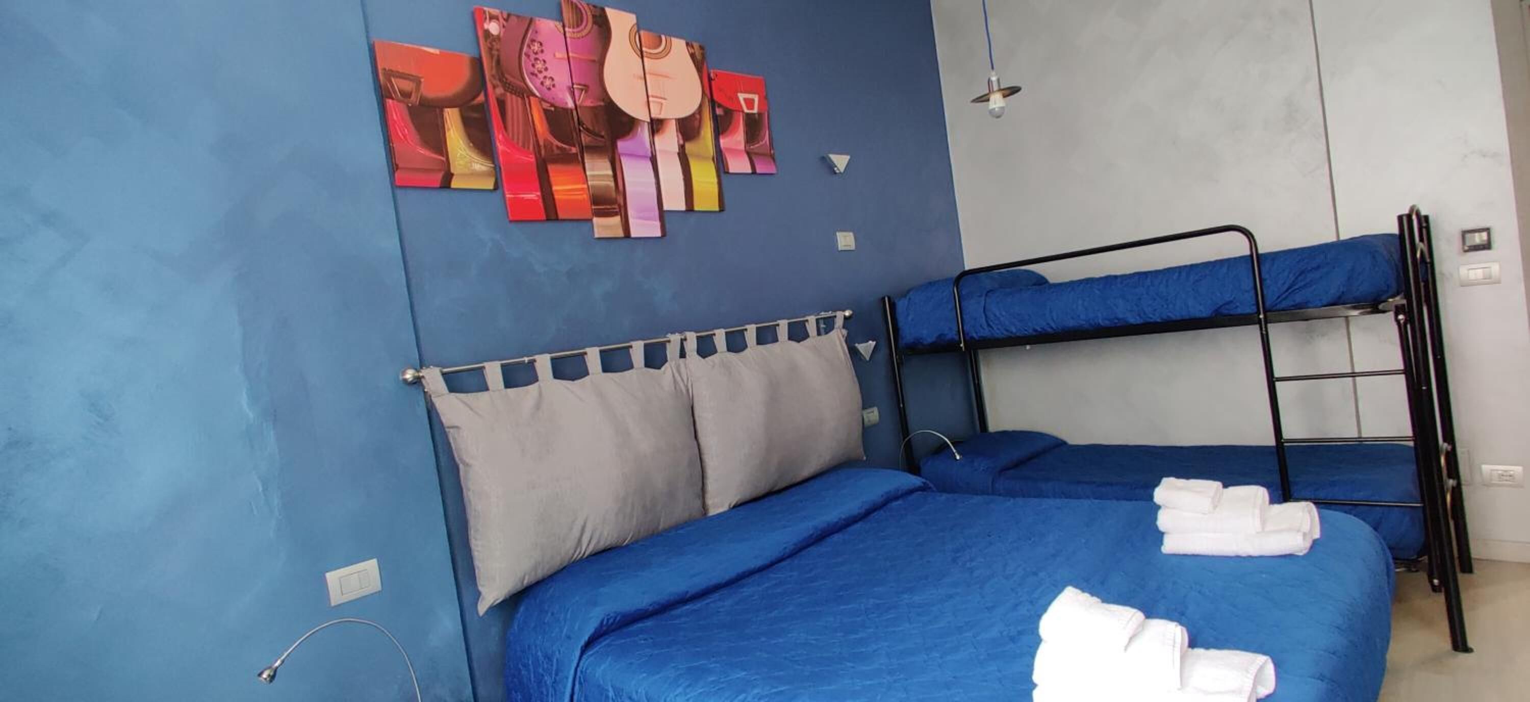 A room with two bunk beds, a blue wall, and a guitar-themed artwork.