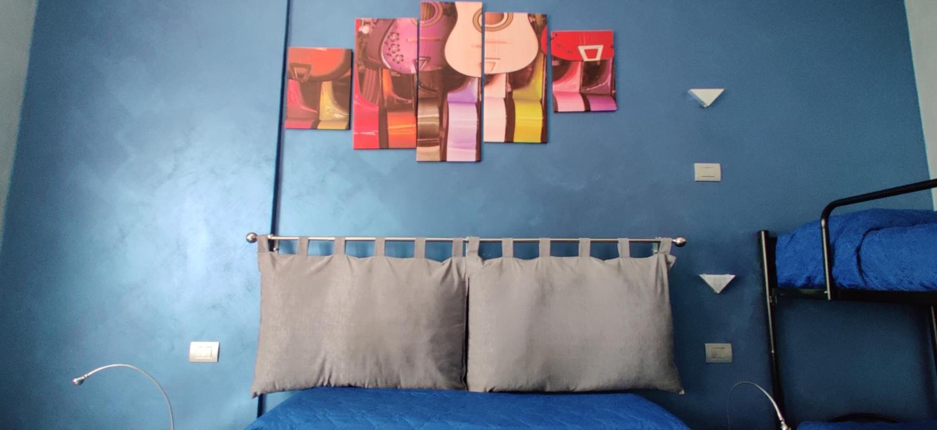 A room with a bunk bed, a blue wall, and a series of colorful artworks.