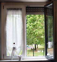 Una ventana con vista a un árbol y un parque.